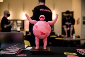 "Dotty" the Cardiff Animation Festival mascot on a table in front of workers at the festival.